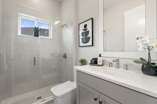 bathroom featuring vanity, a shower with shower door, and toilet