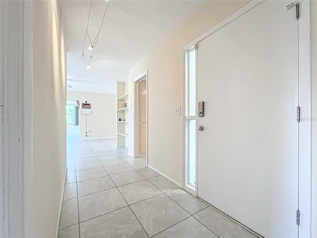 hallway featuring baseboards and light tile patterned floors