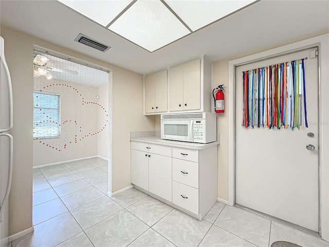 kitchen featuring ceiling fan, light tile patterned floors, and white cabinets