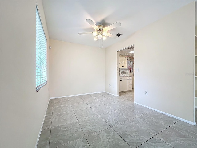 unfurnished room with a ceiling fan, baseboards, and light tile patterned floors
