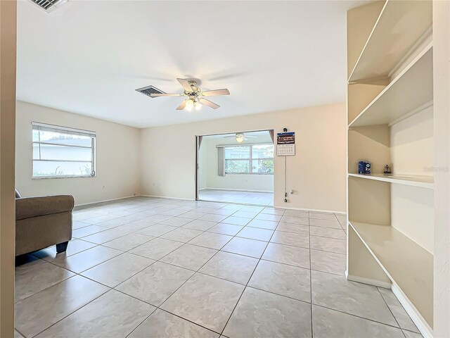 empty room with ceiling fan, light tile patterned floors, and a healthy amount of sunlight