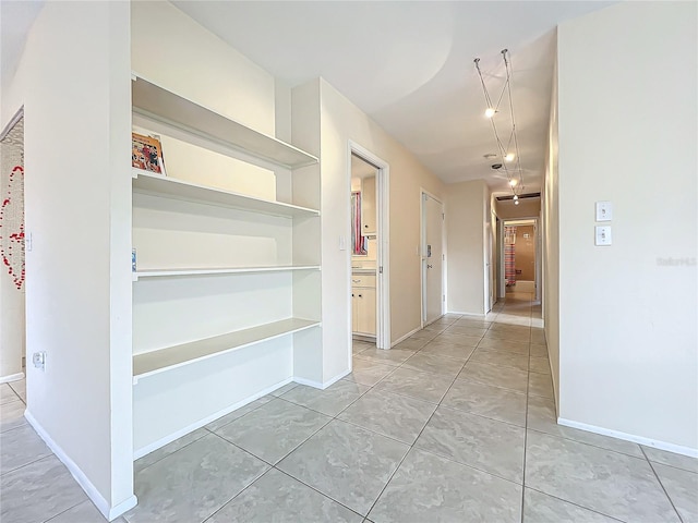 hall featuring baseboards and light tile patterned floors