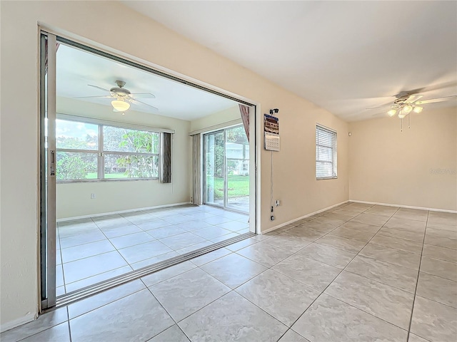 unfurnished room with baseboards, a ceiling fan, and light tile patterned floors