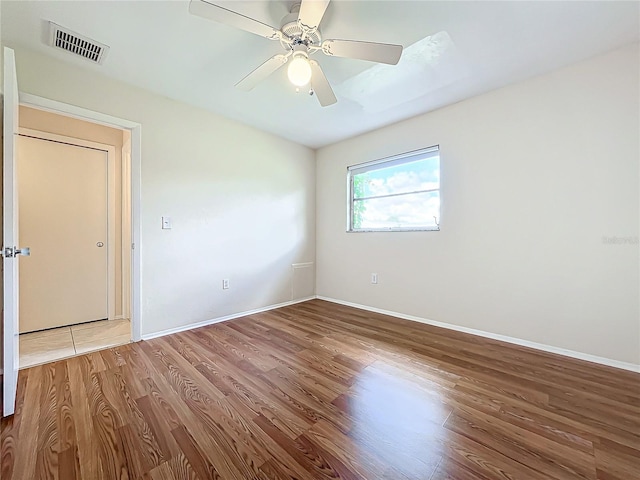 unfurnished room featuring wood finished floors, visible vents, and baseboards