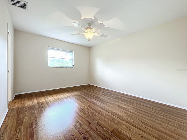 spare room featuring baseboards, a ceiling fan, wood finished floors, and visible vents