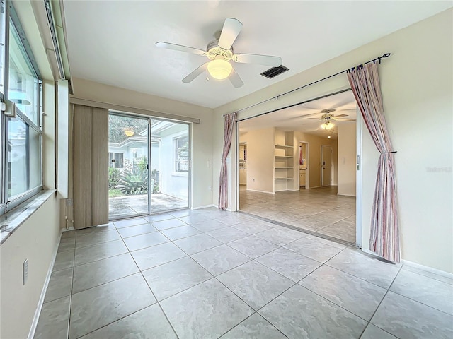 tiled spare room with ceiling fan