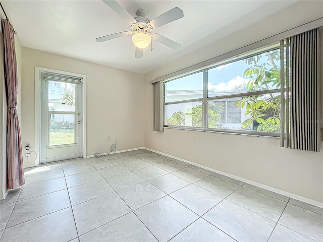 empty room with ceiling fan, baseboards, and light tile patterned floors