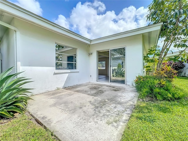 doorway to property with a patio and a lawn