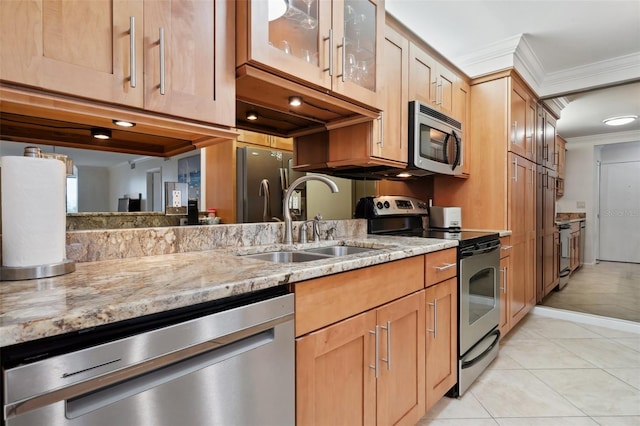 kitchen with appliances with stainless steel finishes, a sink, light stone counters, and ornamental molding