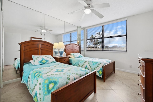 bedroom with light tile patterned floors, ceiling fan, baseboards, and a textured ceiling