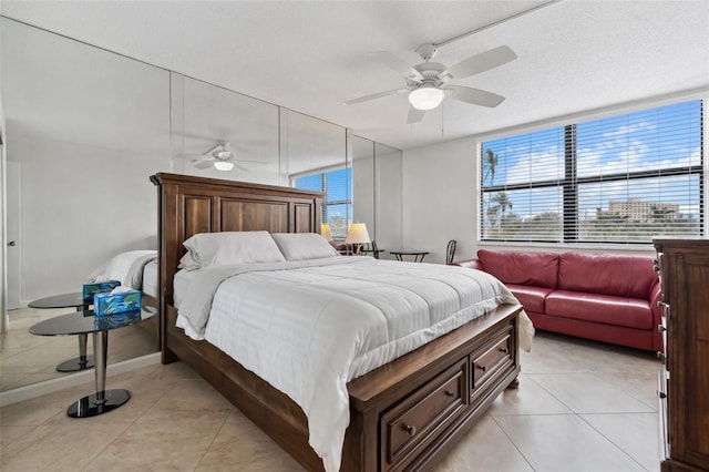 bedroom with multiple windows, ceiling fan, a textured ceiling, and light tile patterned floors