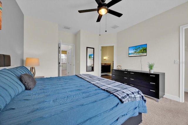 bedroom with ensuite bath, light colored carpet, and ceiling fan