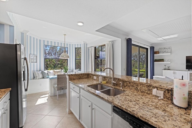 kitchen featuring appliances with stainless steel finishes, light stone counters, sink, pendant lighting, and white cabinetry