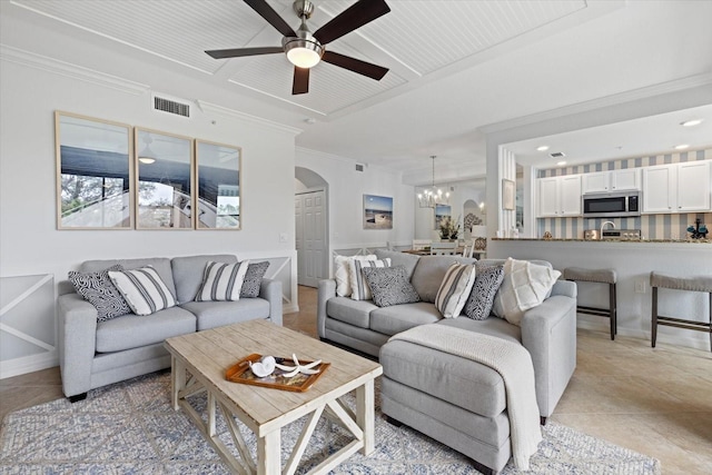 living room featuring ceiling fan with notable chandelier, ornamental molding, and light tile patterned flooring