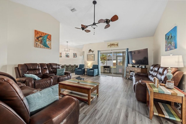 living area featuring a ceiling fan, lofted ceiling, visible vents, and wood finished floors