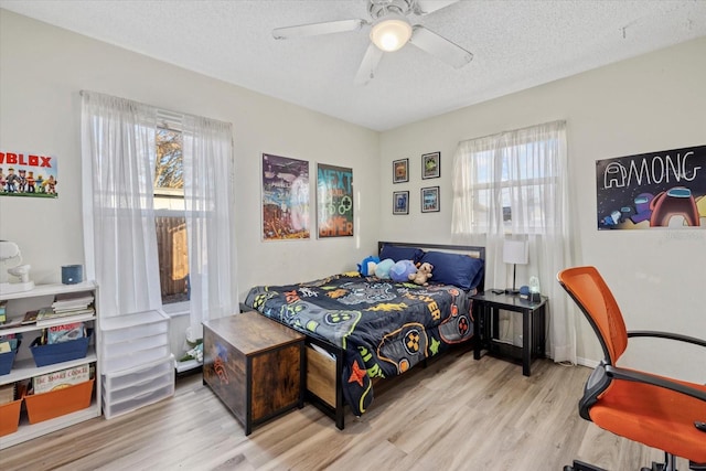 bedroom featuring light hardwood / wood-style flooring, a textured ceiling, and ceiling fan