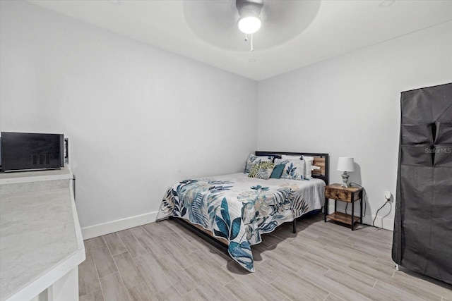 bedroom with a ceiling fan, wood tiled floor, and baseboards