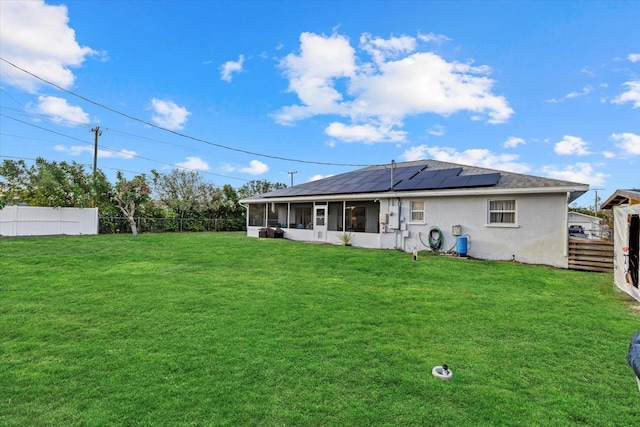 rear view of property with a sunroom, stucco siding, a fenced backyard, and solar panels