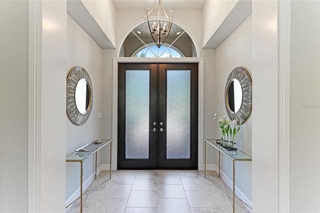 tiled foyer entrance featuring a towering ceiling, french doors, and a chandelier