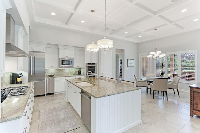 kitchen featuring pendant lighting, built in appliances, a center island with sink, and sink