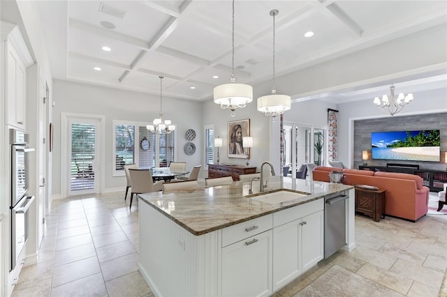 kitchen with light stone counters, pendant lighting, sink, a kitchen island with sink, and white cabinetry