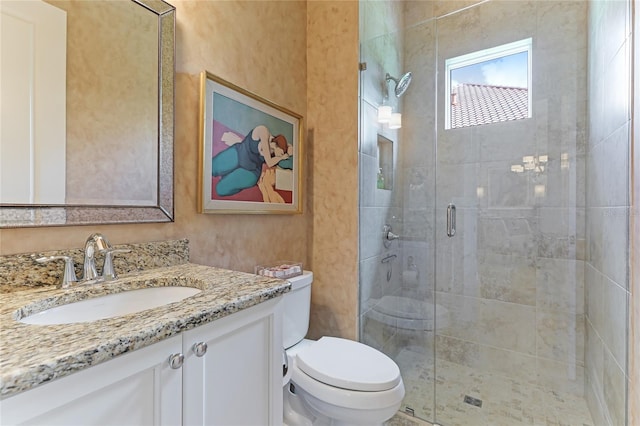 bathroom featuring vanity, toilet, and a shower with door