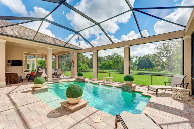 view of pool with ceiling fan, a patio, pool water feature, a yard, and glass enclosure