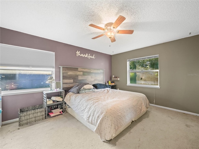 carpeted bedroom featuring ceiling fan and a textured ceiling