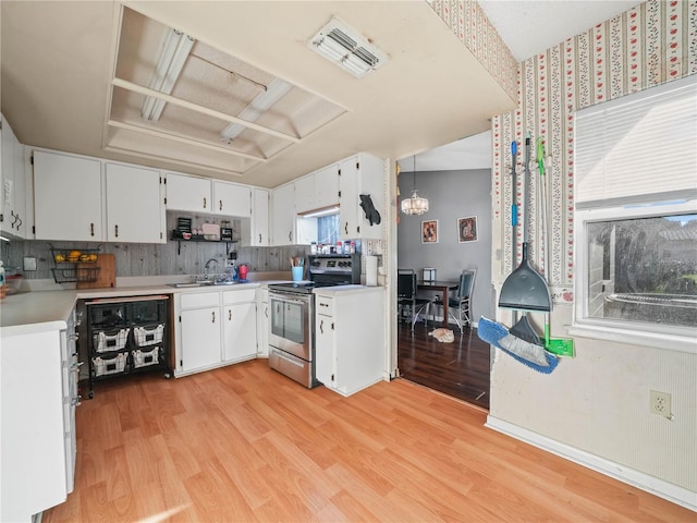 kitchen featuring light hardwood / wood-style floors, sink, electric stove, white cabinetry, and hanging light fixtures