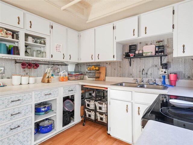 kitchen with light wood-type flooring, black electric range, sink, and white cabinets