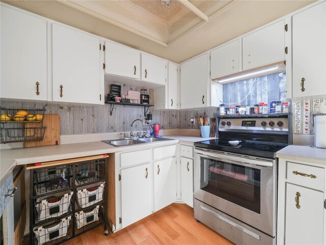 kitchen with decorative backsplash, white cabinetry, light hardwood / wood-style flooring, sink, and electric range