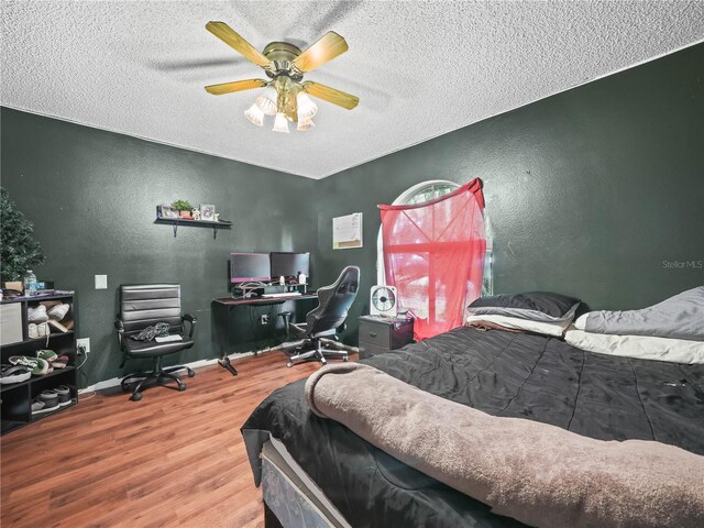 bedroom featuring ceiling fan, hardwood / wood-style flooring, and a textured ceiling