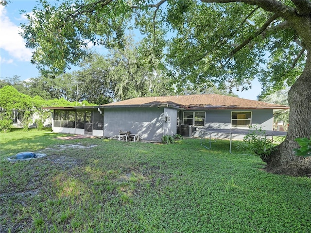 rear view of property with a sunroom, a lawn, and central air condition unit