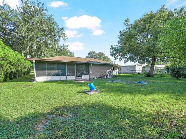 rear view of property with a sunroom and a yard