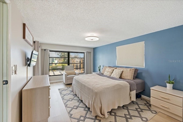 bedroom with light wood-type flooring and a textured ceiling