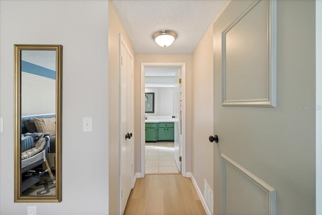 hall featuring a textured ceiling and light hardwood / wood-style flooring