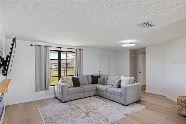 living room with light hardwood / wood-style floors and a textured ceiling