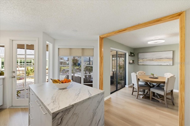 kitchen featuring white cabinets, light hardwood / wood-style floors, a textured ceiling, and a center island