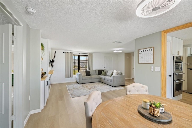 dining area with light hardwood / wood-style floors and a textured ceiling