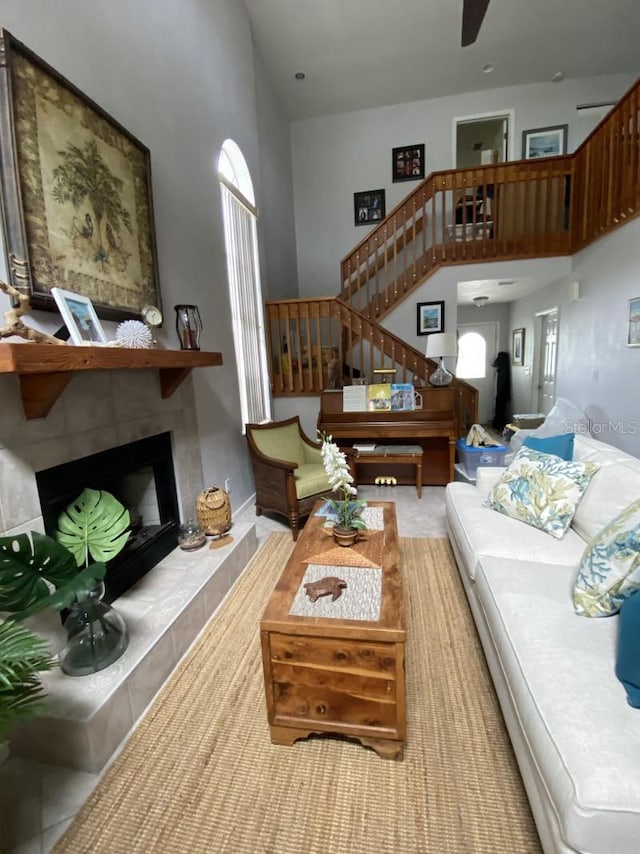 living room with ceiling fan, a fireplace, a healthy amount of sunlight, and a high ceiling