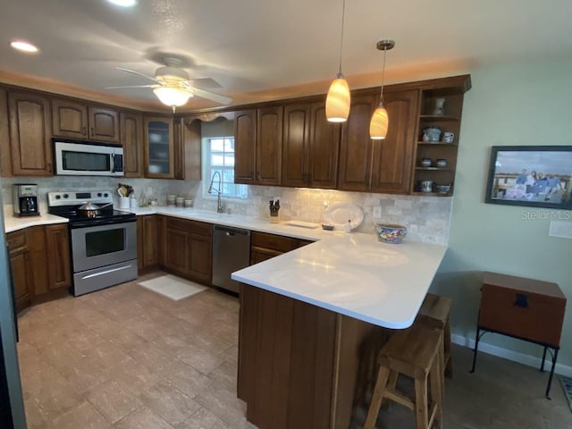 kitchen featuring ceiling fan, sink, stainless steel appliances, kitchen peninsula, and pendant lighting