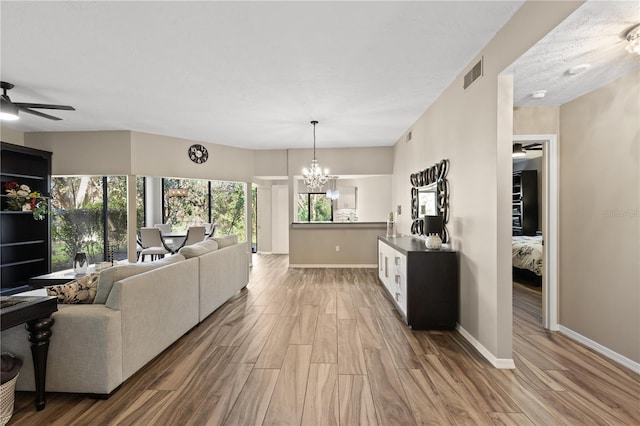 living room featuring wood-type flooring and ceiling fan with notable chandelier