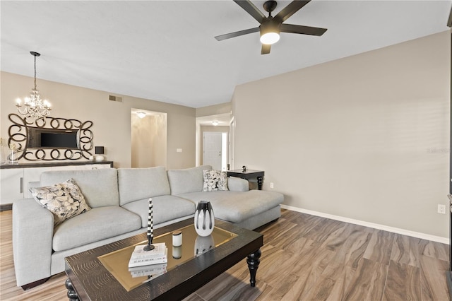 living room featuring ceiling fan with notable chandelier and hardwood / wood-style floors