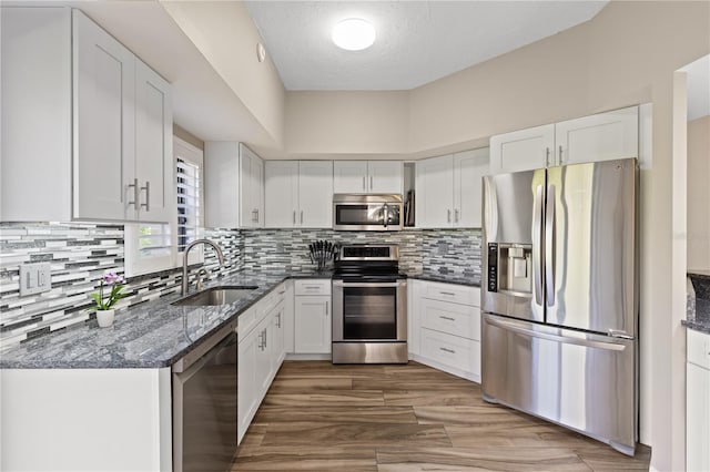 kitchen featuring appliances with stainless steel finishes, a textured ceiling, dark stone counters, and white cabinets