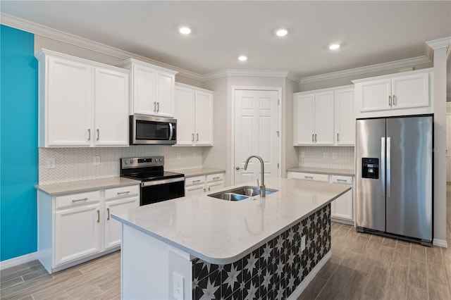 kitchen with white cabinets, a center island with sink, light stone counters, appliances with stainless steel finishes, and sink