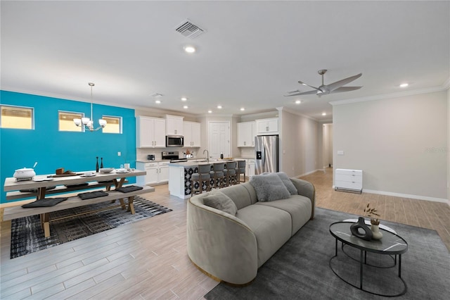 living room with light hardwood / wood-style floors, ornamental molding, sink, and ceiling fan with notable chandelier