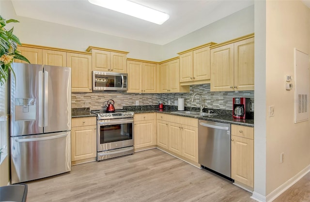 kitchen with stainless steel appliances, decorative backsplash, sink, light wood-type flooring, and light brown cabinetry