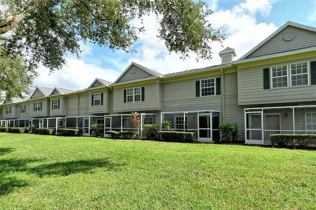 rear view of property featuring a lawn and a sunroom