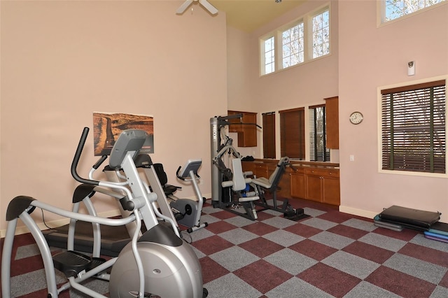 workout area featuring dark colored carpet and a high ceiling