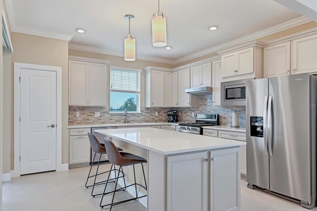 kitchen with backsplash, crown molding, a kitchen island, and appliances with stainless steel finishes